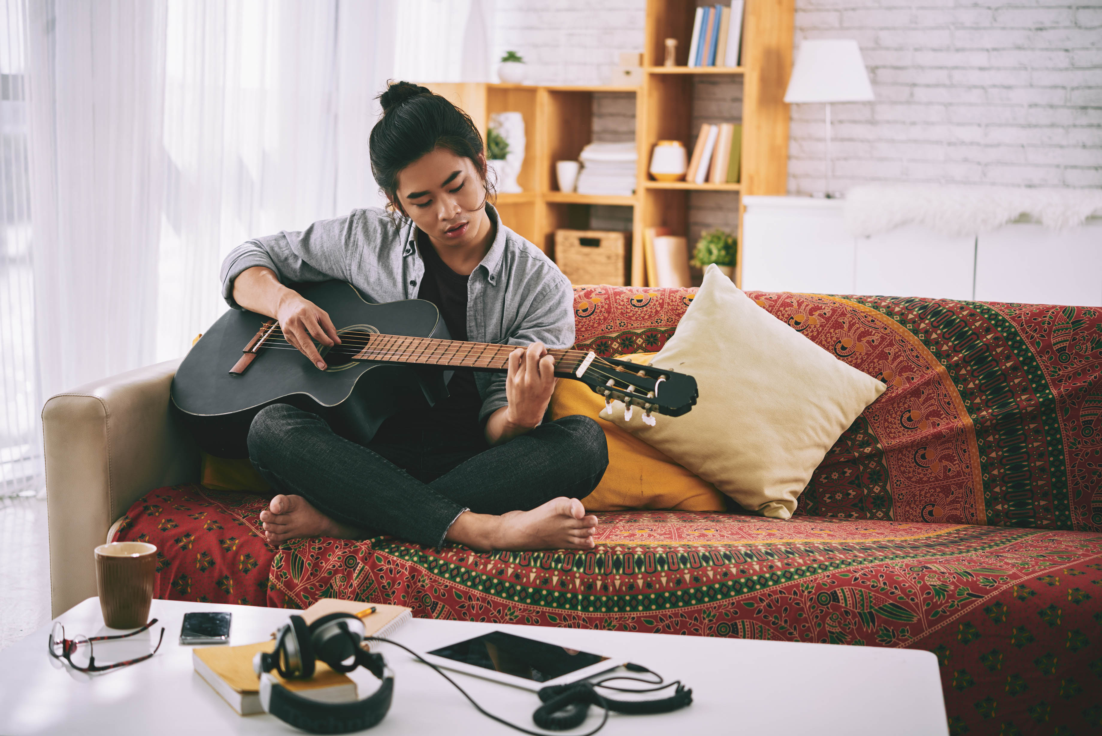 man plays guitar on his couch