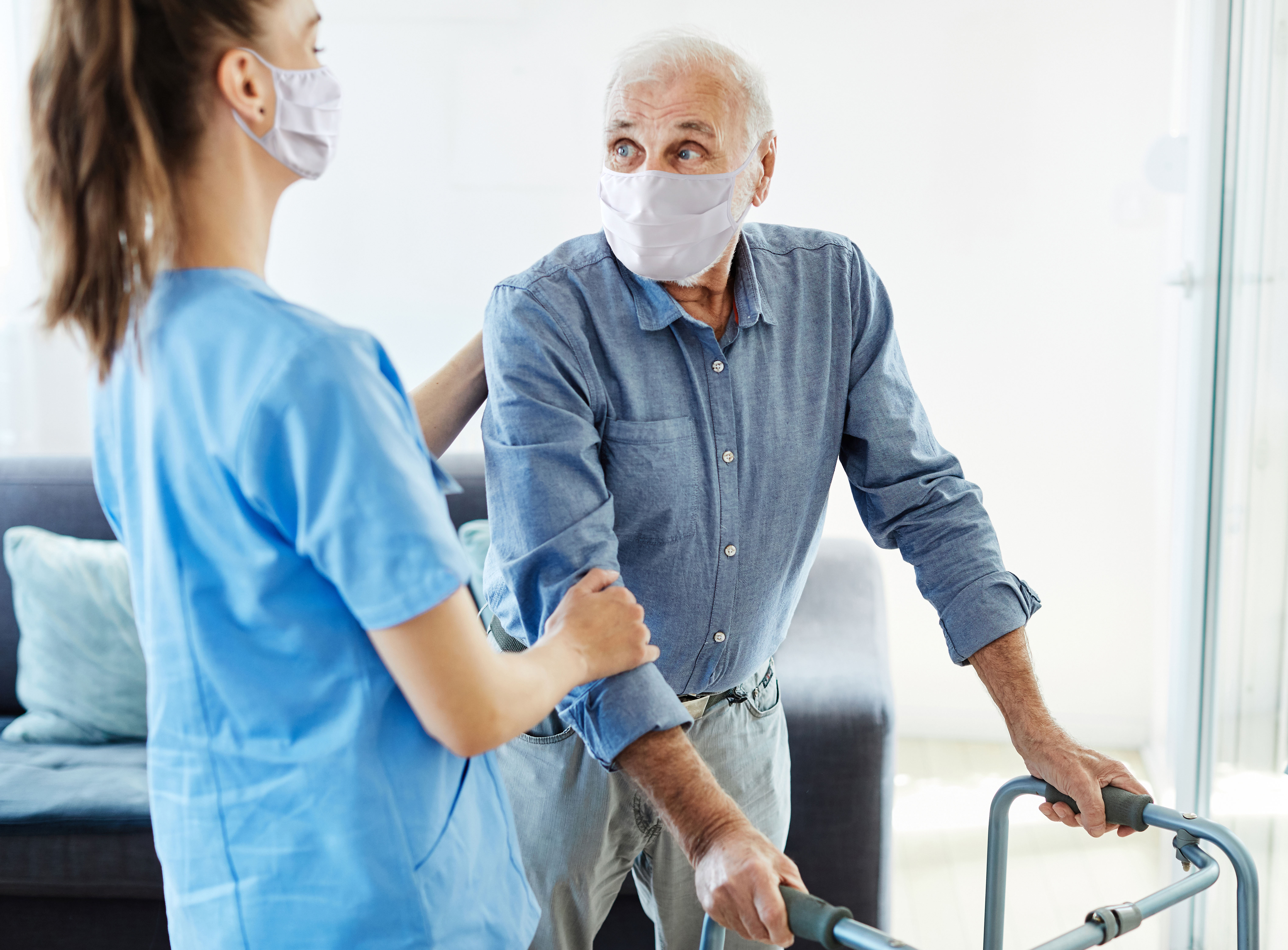 Aged care nurse assists patient with walker
