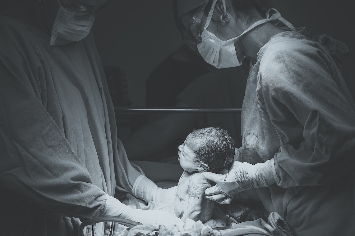 Photograph of midwives assisting in delivery of baby