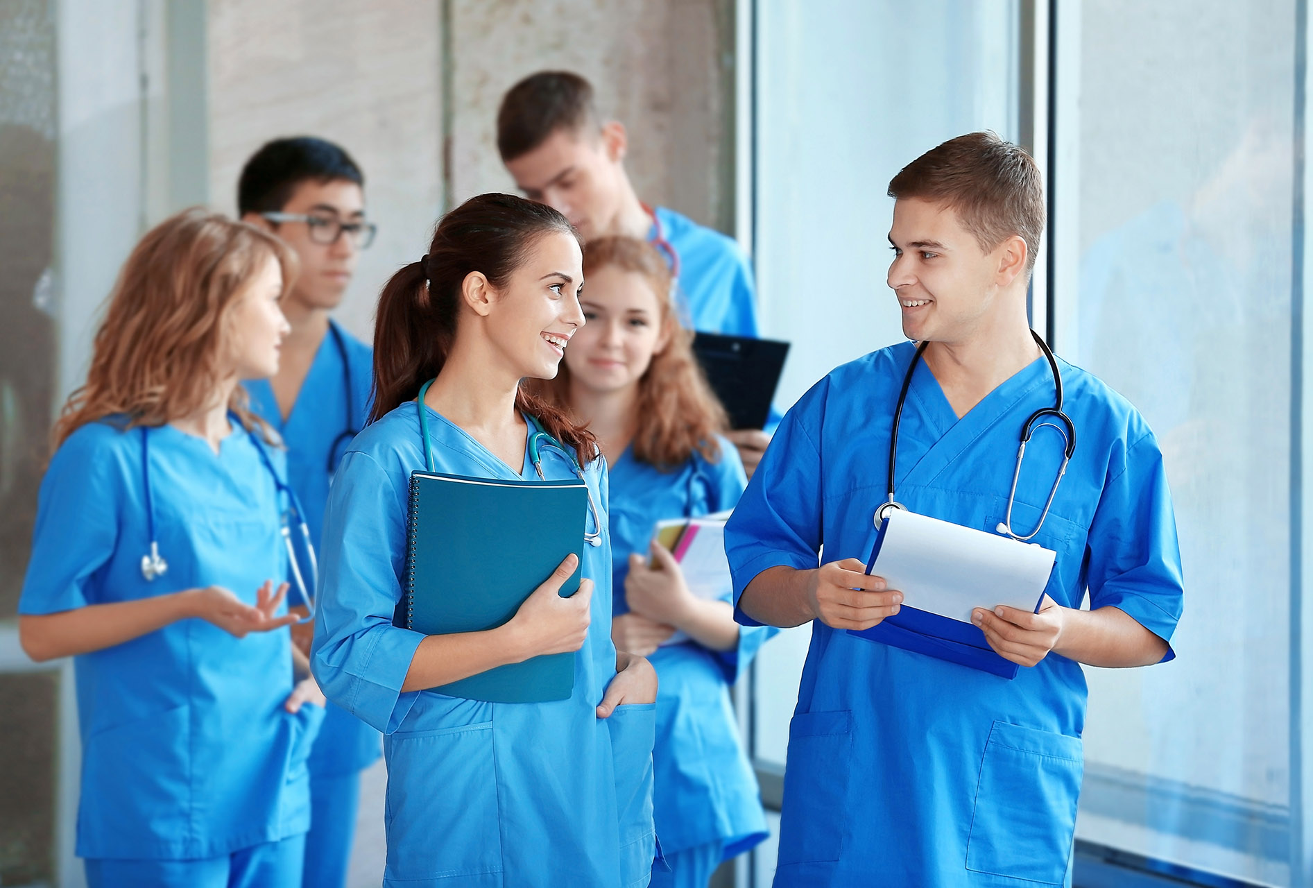 a group of young nurses chatting with clipboards